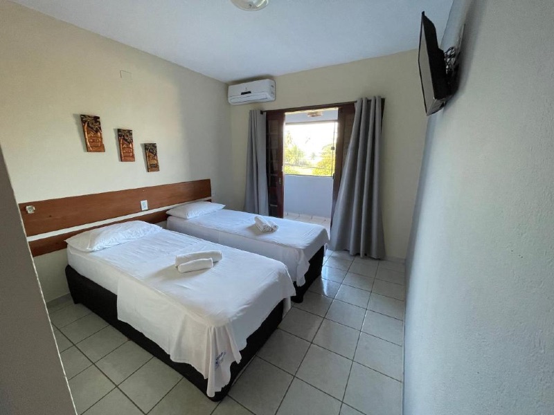 Quarto da pousada Costa dos Corais com duas camas de solteiro, TV e ar-condicionado