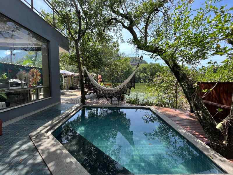 Piscina ao ar livre com rede na Casanova Residence, no Rio de Janeiro, em meio a árvores