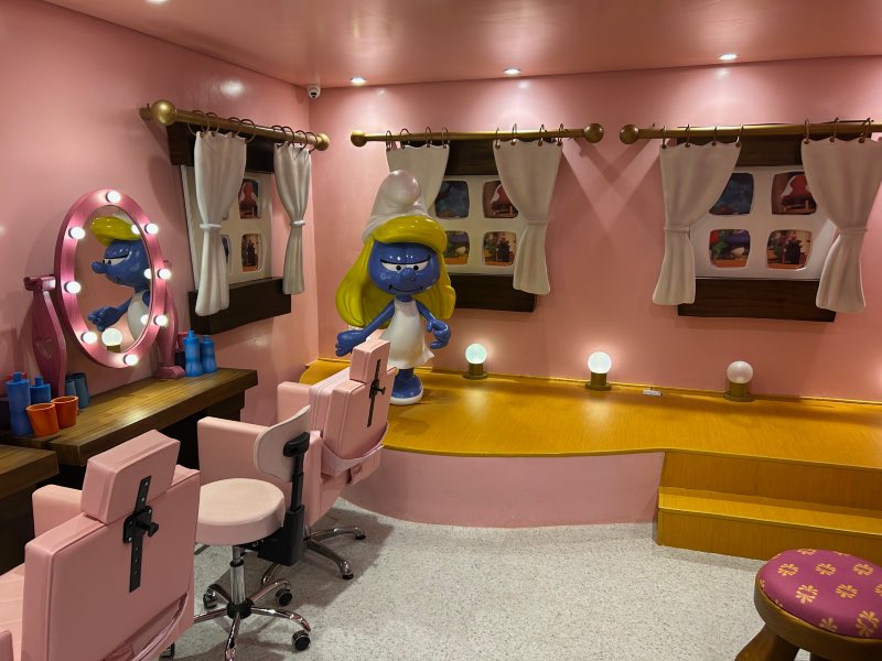 Salão da Smurfete vazio com paredes rosadas, palco e espelhos com luzes