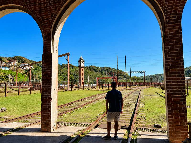 Homem de costas na estação de trem com a Torre do Relógio ao fundo